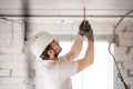 Electrician installer with a tool in his hands, working with cable on the construction site Royalty Free Stock Photo