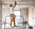 Electrician installer with a tool in his hands, working with cable on the construction site Royalty Free Stock Photo