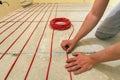 Electrician installing heating red electrical cable wire on cement floor in unfinished room. Renovation and construction, Royalty Free Stock Photo