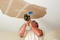 Electrician installing light fixture on ceiling