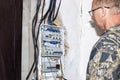 An electrician installs an electrical panel built into the wall of the house. A device for controlling electricity and protecting