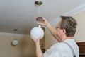 Electrician is instilling a ceiling lamp.