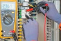 Electrician and instrument worker wearing safety gloves measuring voltage and checking electric circuit by using digital meter