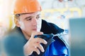 Electrician or instrumentation fitter with screwdriver adjusts operation of pressure gauge at gas industrial facility