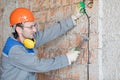 Electrician man worker installing electrical cable at house wall Royalty Free Stock Photo