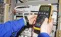 Electrician measures voltage by tester. multimeter is in hands of engineer in electrical cabinet Royalty Free Stock Photo