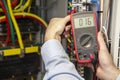 Electrician measuring voltage in fuse board close-up. Male technician examining fusebox with multimeter probe Royalty Free Stock Photo