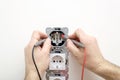 Electrician measuring voltage in the outlet using a multimeter in hands