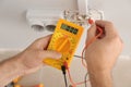 Electrician measuring voltage in socket indoors, closeup