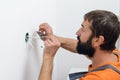 Electrician mounting electric sockets on the white wall. Electrician wiring a new build