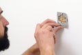 Electrician mounting electric sockets on the white wall. Electrician wiring a new build