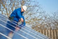 Electrician mounting solar panel on roof of modern house