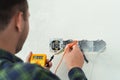 Electrician mounts a new socket on a white wall.