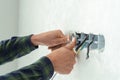 Electrician mounts a new socket on a white wall