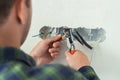 Electrician mounts a new socket on a white wall