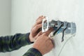 Electrician mounts a new socket on a white wall