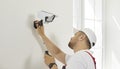 Electrician worker installs and screws video surveillance camera with backlight on wall.