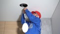 Electrician with red helmet checking lighting led panel at home
