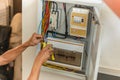 Electrician repairing electrical box with pliers at home.