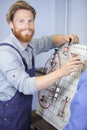 electrician repairing fuse box with screwdriver indoors