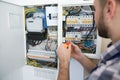 Electrician repairing fuse box with screwdriver indoors Royalty Free Stock Photo