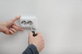 Electrician repairing wall sockets on white background