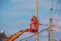 Electrician repairing wire of the power line with bucket hydraulic lifting platform on blue sky Royalty Free Stock Photo