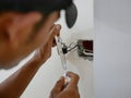 An electrician`s hand holding on a neon-lamp type tester, screwdriver, testing electric current in a light switch