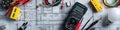 Electrician's toolkit: multimeter, wires, light bulb, and blueprints on a desk Royalty Free Stock Photo