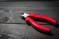 Electrician's wire pliers with red handles on a dark wood texture background Royalty Free Stock Photo