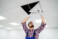 Electrician On Stepladder Installs Lighting To The Ceiling