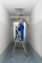 Electrician on stepladder installs lighting to the ceiling Royalty Free Stock Photo