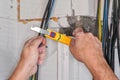 Electrician stripping insulation from power cables with wire stripper tool. Detail on his hands Royalty Free Stock Photo