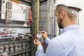 Electrician technician in fuse box. Maintenance engineer in control panel. Worker is testing automation equipment Royalty Free Stock Photo