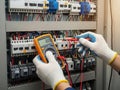 Electrician using a multimeter to test voltage in an electrical panel Royalty Free Stock Photo