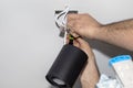 An electrician, using a screwdriver, assembles modern LED lighting in the shape of a tube, painted with matt black paint, with a c Royalty Free Stock Photo