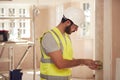 Electrician Wearing Hard Hat Fitting Light Switch At New Build Property Royalty Free Stock Photo