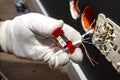 An electrician in white gloves is installing a network cable for the RJ45 module to the computer socket in the room.