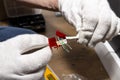 An electrician in white gloves is installing a network cable for the RJ45 module to the computer socket in the room.