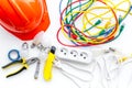 Electrician work concept. Hard hat, tools, cabel, socket outlet on white background top view Royalty Free Stock Photo