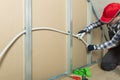 Electrician at work - installing electricity wire into plasterboard wall in attic