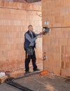 An electrician at work is prepared to install sockets in unfinished house built of clay block bricks. Worker ready for wiring