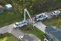 Electrician workers repairing damaged power lines using bucket trucks after hurricane Ian in Florida residential area