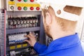 Electrician working in white helmet switches the switch in the electrical cabinet. The engineer works