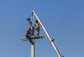 Electricians climbing work in the height on concrete electric power pole with crane