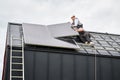 Electricians connecting cables while installing photovoltaic solar panels on roof of house. Royalty Free Stock Photo