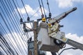 Electricians in crane are working and installation of high voltage electric lines, transformer and telephone cables on pole in the