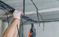 Electricians are fixing electrical cables to the ceiling.