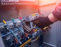 Electricians hands testing switches in electric box. Electrical panel with fuses