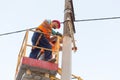 Electricians on the pillars install the mount for the power line. Professional electricians work on the tower